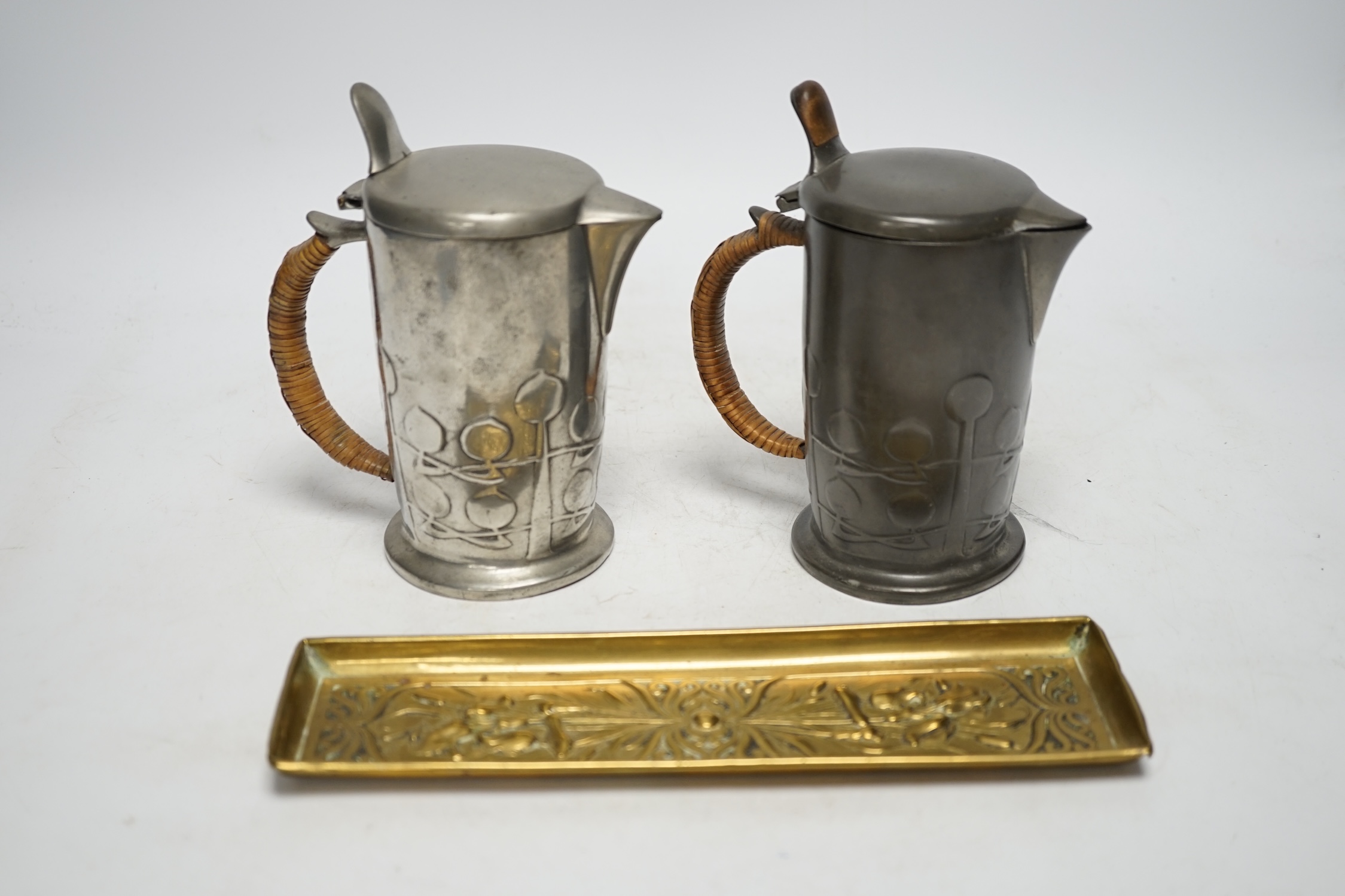 Archibald Knox (1864-1933) for Liberty & Co, two Tudric hot water jugs and an Art Nouveau brass pen tray, tray 24cm long (3). Condition - fair to good